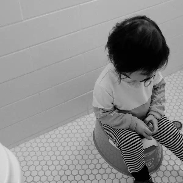 Criança fazendo o treinamento de desfralde sentada no penico